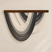 Charcoal and slate open fan wall hanging with a cream center on a pale wall