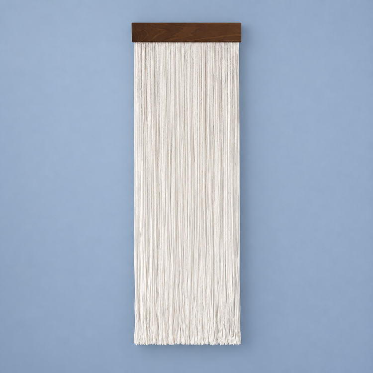 Cream straight cord fringe wall hanging on a dark wood batten against a blue wall