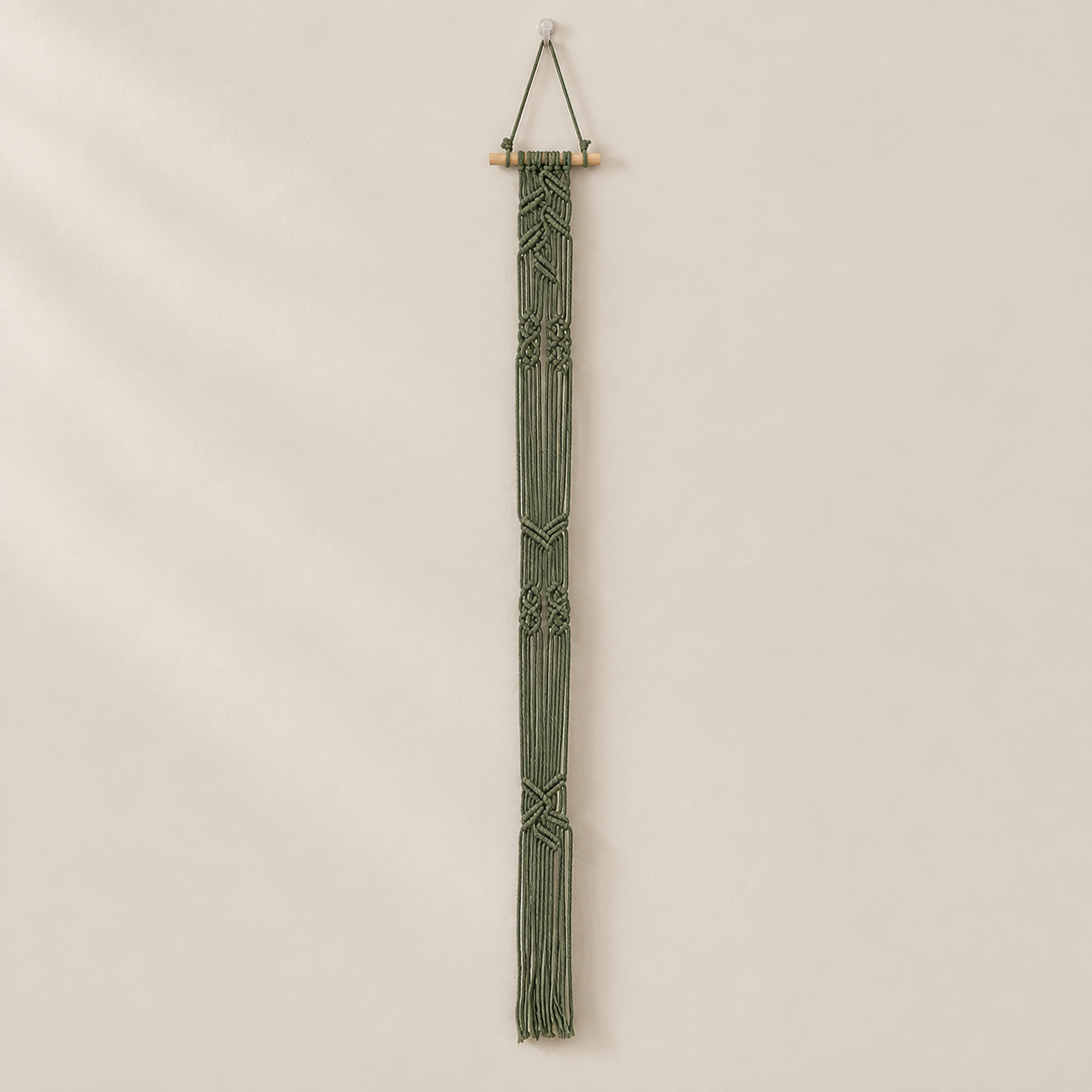 Deep green braided macrame column with no hat loops on a warm neutral wall
