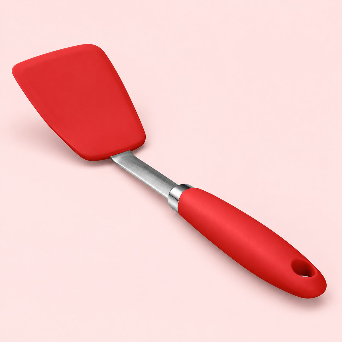 One red silicone turner spatula on a pale blush studio background.