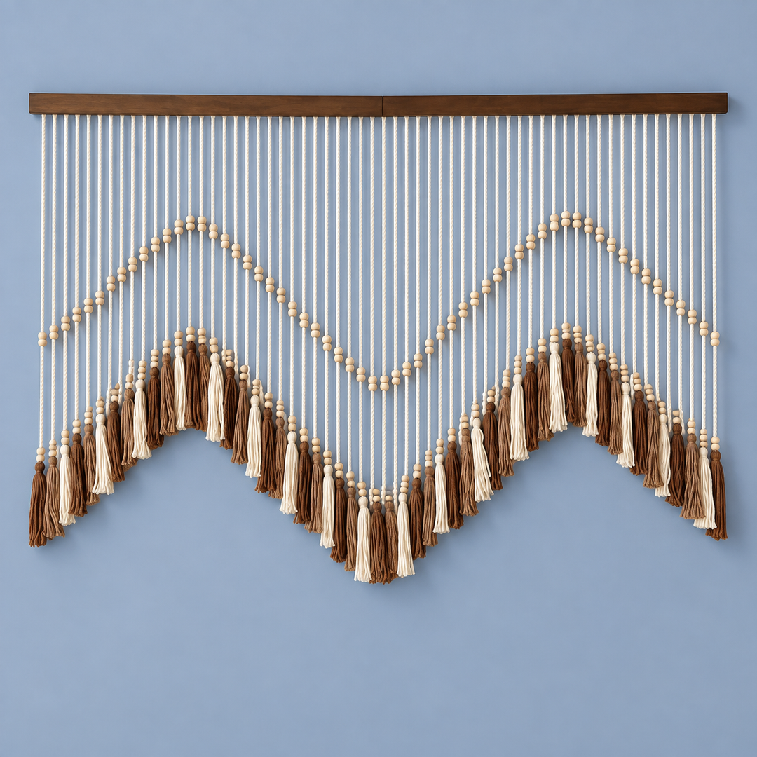 A bohemian-style wall hanging macrame wall decor with a dark wood top bar, cream and brown cord strands, and tassel accents, displayed against a solid light blue wall.