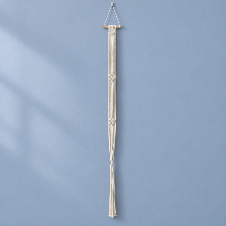 Cream braided macrame column hanging from a dowel against a blue background