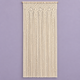 Cream macrame wall hanging with intricate woven patterns and long fringe, displayed against a solid lavender background.