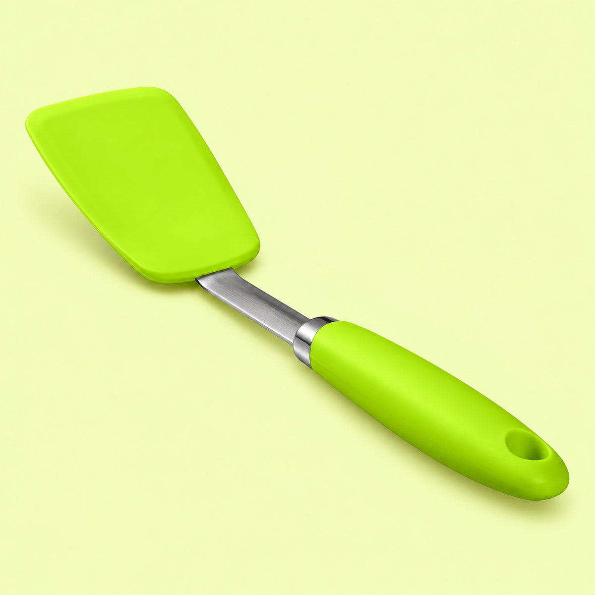 One grass-green silicone turner spatula on a pale chartreuse studio background.