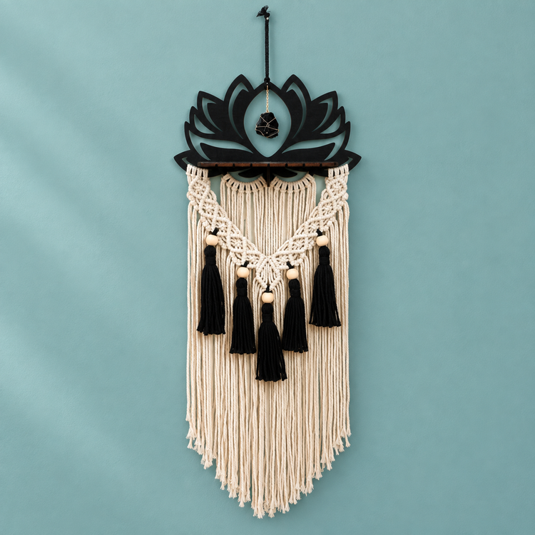 Black laser cut lotus above a wooden ledge with black tassels on a teal wall