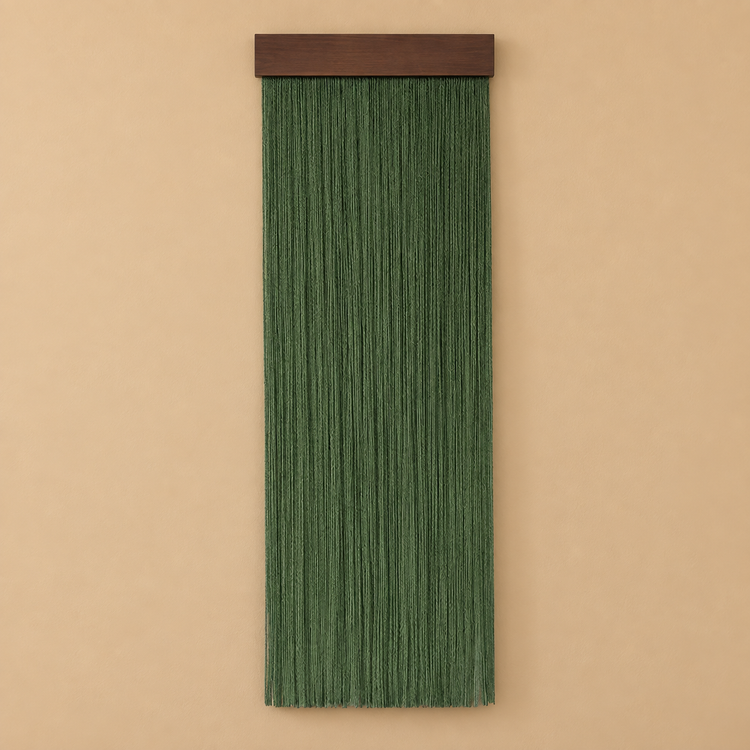 Forest green fringe wall hanging on a dark wood batten against a sand colored wall