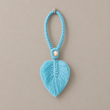 A light blue faux fur heart-shaped hanging ornament with a braided cord loop and a small white bead, shown against a solid taupe background.