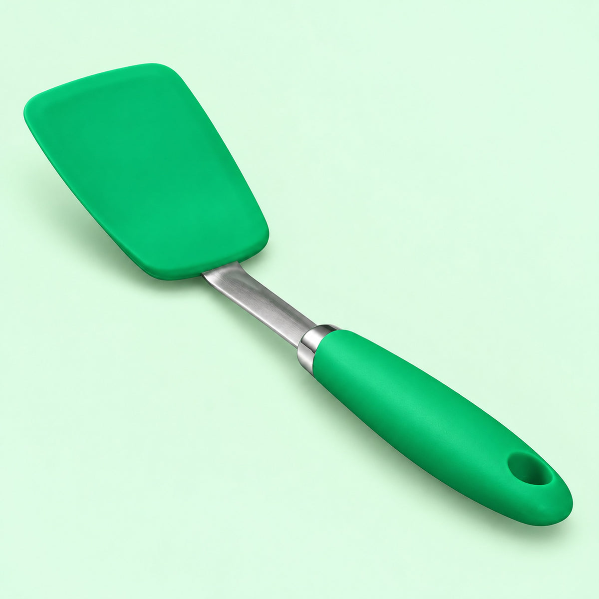One green silicone turner spatula on a pale mint studio background.