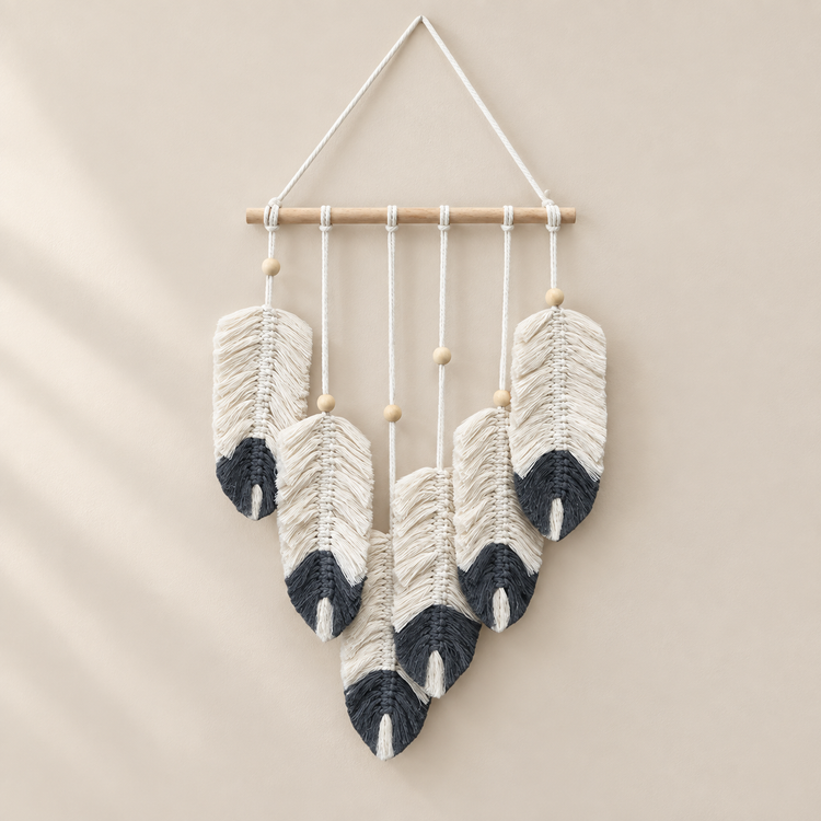 Cream macrame feathers with navy charcoal dipped tips on a pale wall