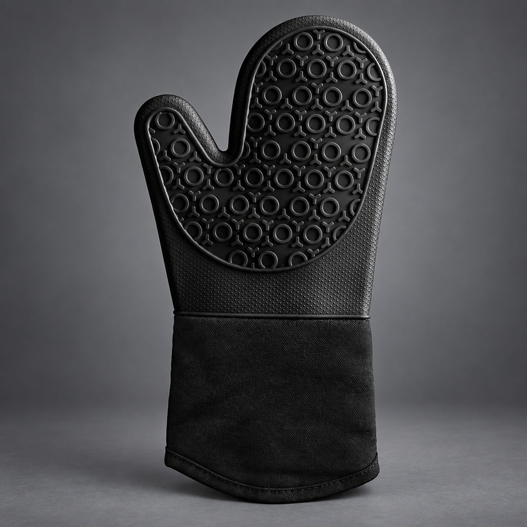 A single black oven mitt with a textured, circular-patterned non-slip grip and a solid black fabric cuff, photographed against a dark gray studio background.