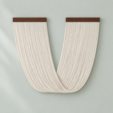 A U-shaped wall hanging made of many narrow cream-colored hanging cords or threads, with two dark brown horizontal bands at the top, shown against a pale green background.