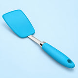 One blue silicone turner spatula on a pale sky-blue studio background.