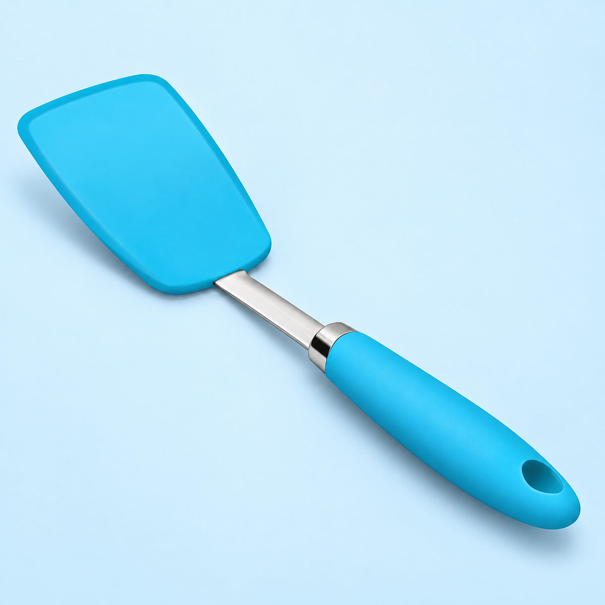 One blue silicone turner spatula on a pale sky-blue studio background.
