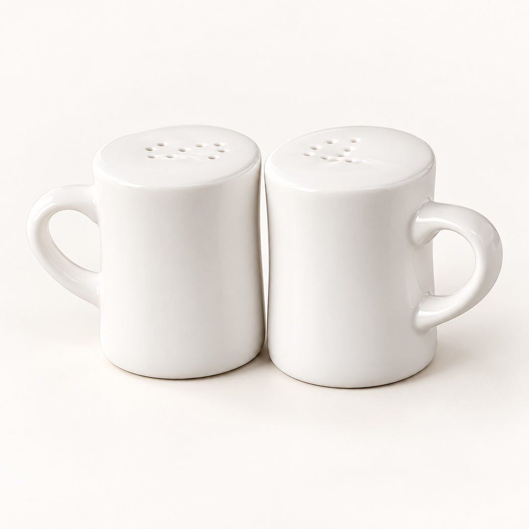 A pair of white ceramic mugs with matching perforated lids, shown side by side on a clean white background.