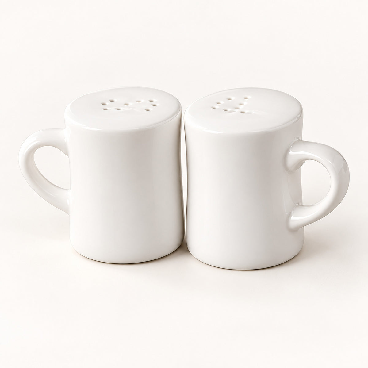 A pair of white ceramic mugs with matching perforated lids, shown side by side on a clean white background.