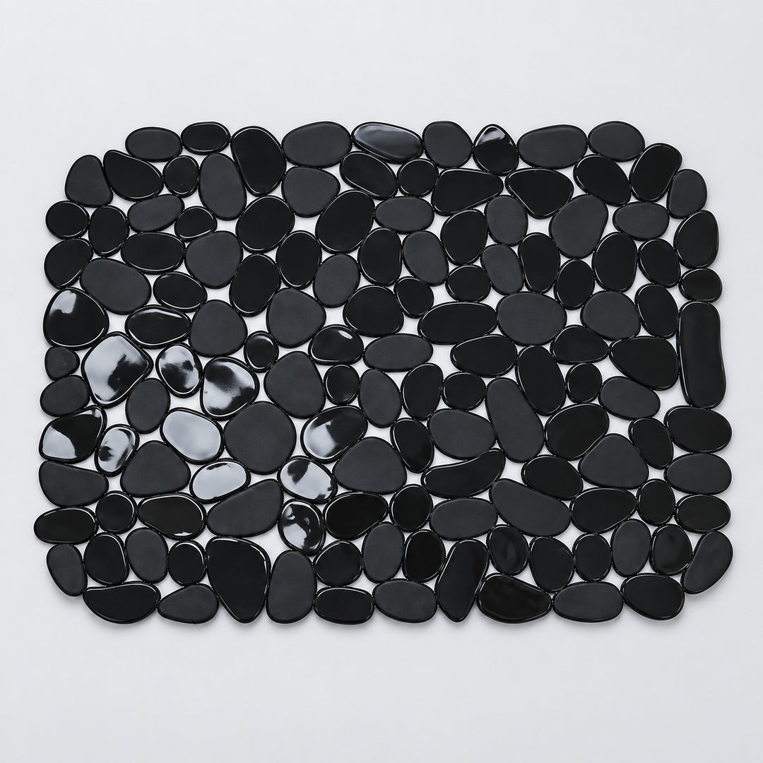 A rectangular mat made of glossy black pebble-shaped stones, photographed from above on a plain light background.