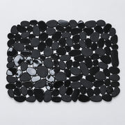 A rectangular mat made of glossy black pebble-shaped stones, photographed from above on a plain light background.