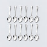 Twelve silver teaspoons arranged in two rows of six on a pale gray background.