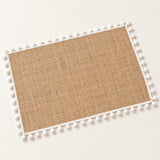One tan placemat with white pom pom trim, 30 x 45 cm.