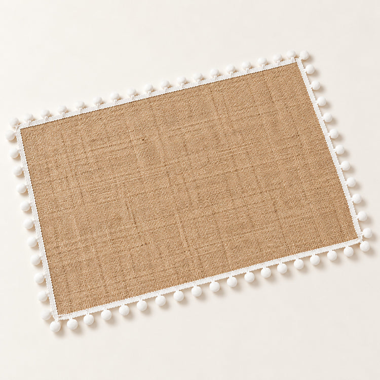 One tan placemat with white pom pom trim, 30 x 45 cm.