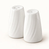 A pair of white ceramic salt and pepper shakers with a textured, wavy vertical rib design, shown on a clean off-white background.