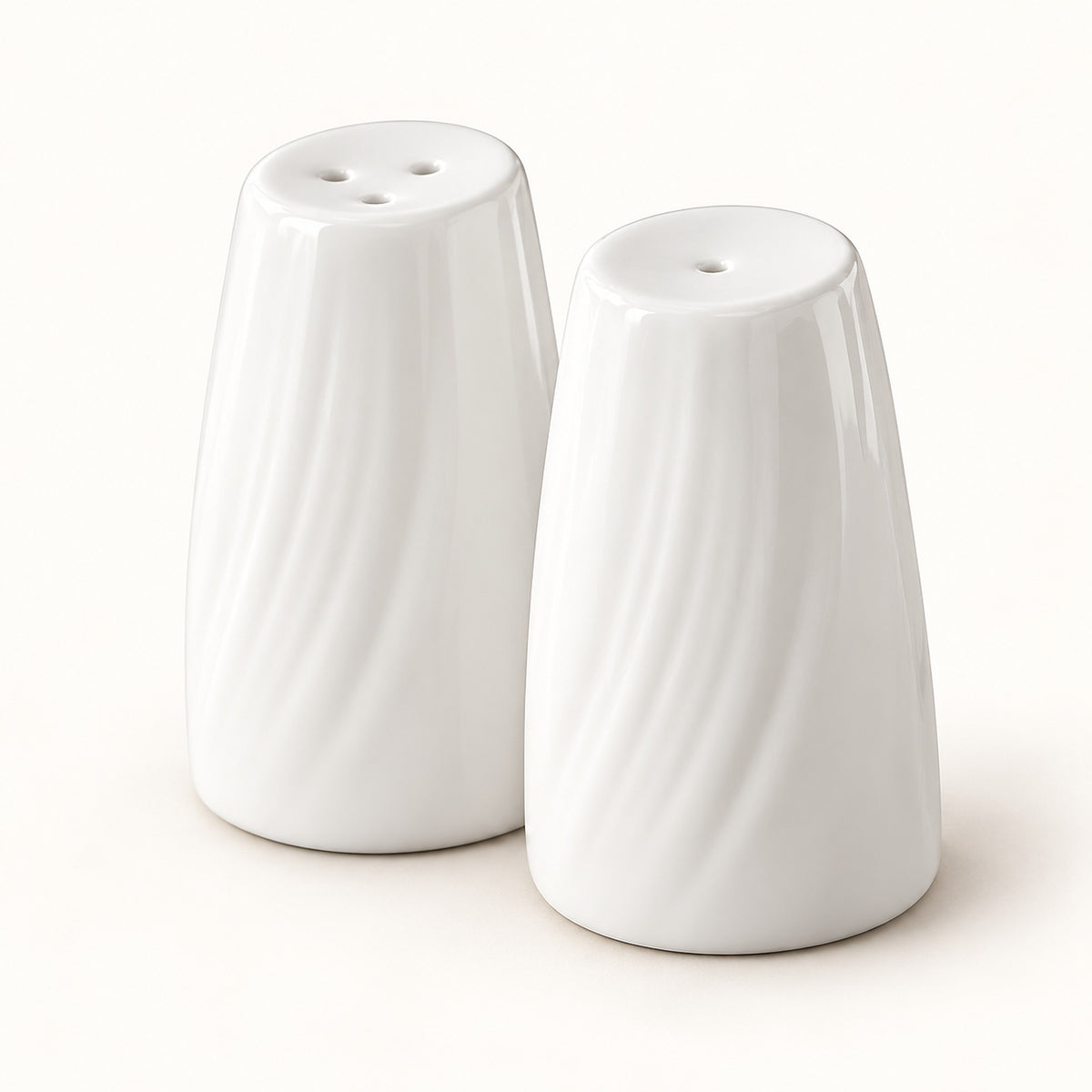 A pair of white ceramic salt and pepper shakers with a textured, wavy vertical rib design, shown on a clean off-white background.