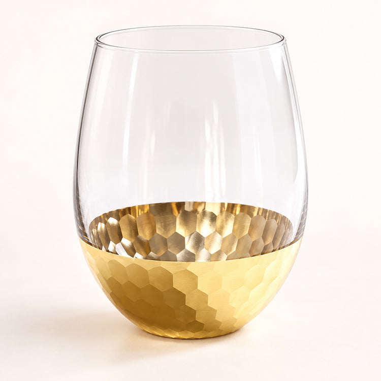 A clear stemless wine glass with a hammered gold metallic base, shown on a clean white background.