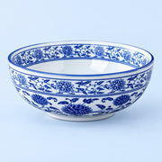 A white ceramic bowl decorated with traditional blue floral and vine patterns, shown against a light blue background.