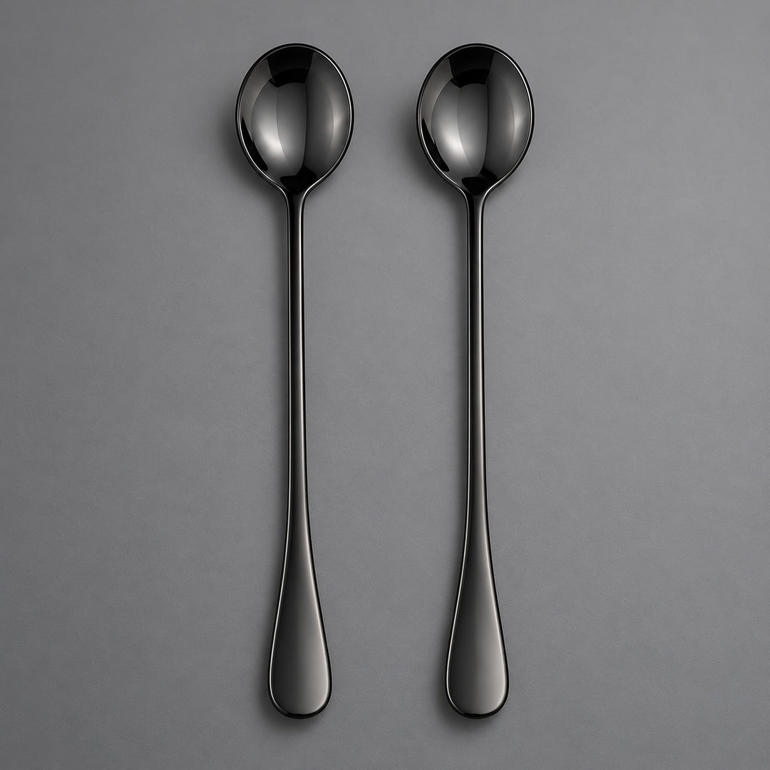 Two slim black metal spoons with a glossy finish, arranged vertically side-by-side on a neutral gray background.