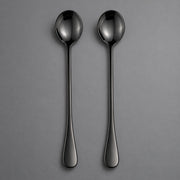 Two slim black metal spoons with a glossy finish, arranged vertically side-by-side on a neutral gray background.