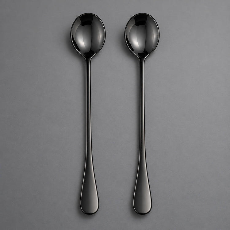 Two slim black metal spoons with a glossy finish, arranged vertically side-by-side on a neutral gray background.