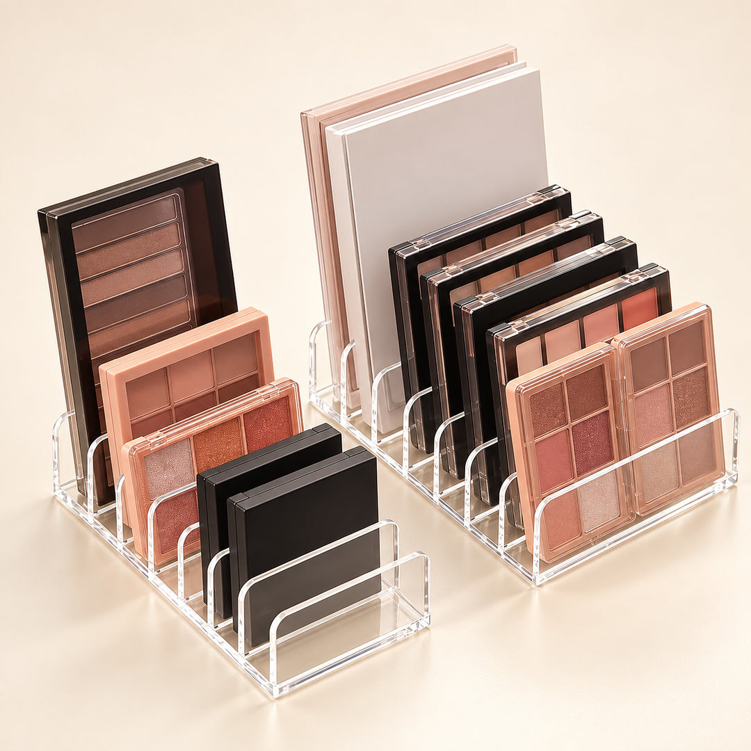 Two clear acrylic makeup organizer stands holding multiple eyeshadow palettes and compact powders in neutral and pink tones, arranged on a warm beige studio background.