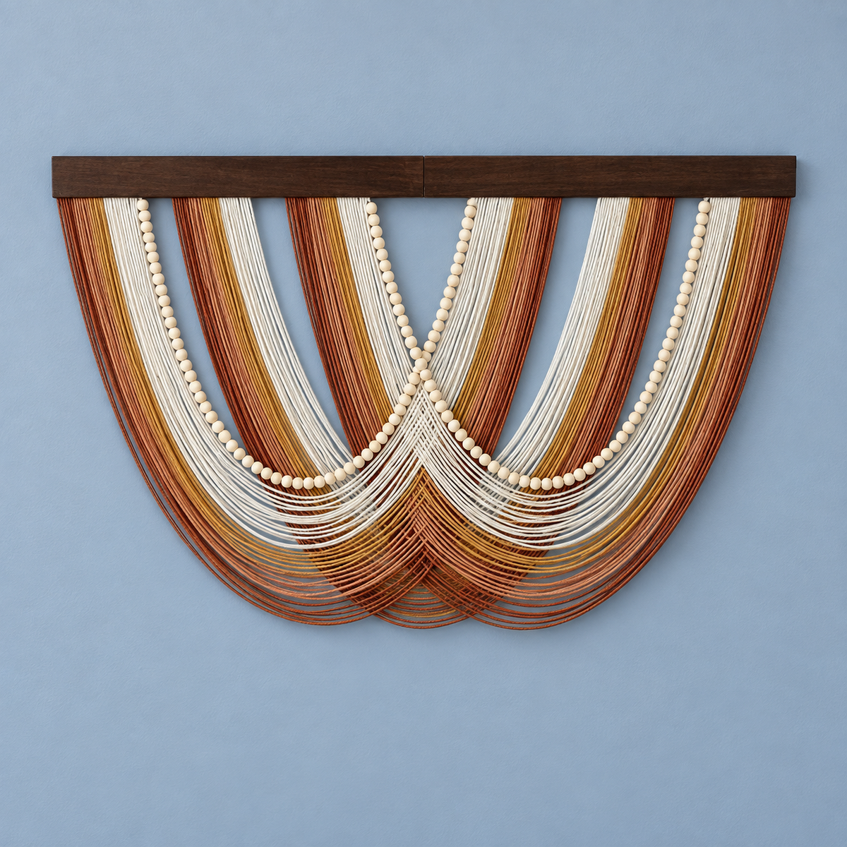 A bohemian-style wall hanging featuring multiple curved strands of brown, tan, and cream cord with central rows of white wooden beads, suspended from a dark wood top bar against a light blue wall.