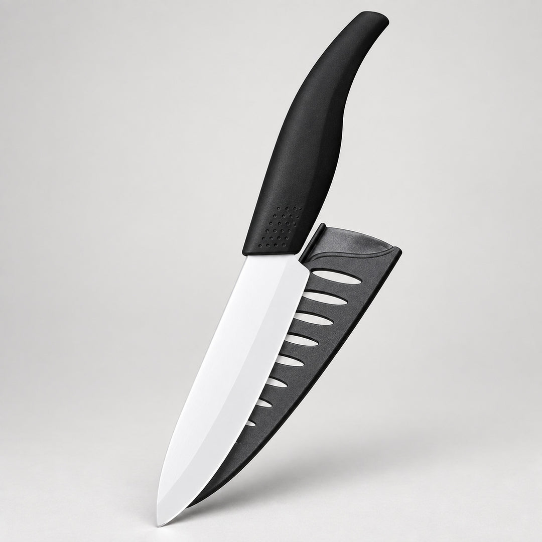 A kitchen knife with a black handle and a black sheath featuring diagonal cutouts, displayed against a neutral light gray background.
