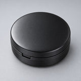 Black round case on a pale gray studio background.