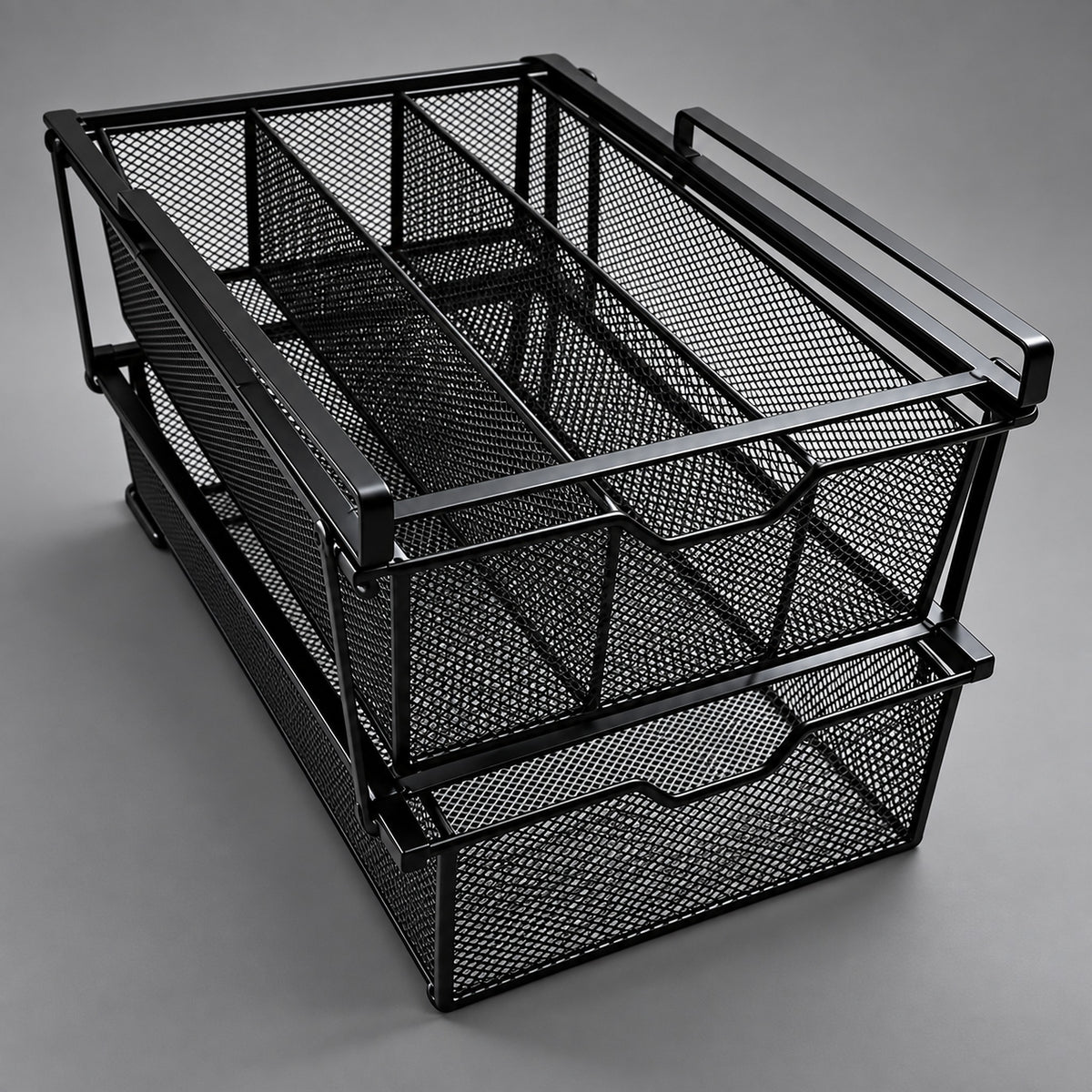 A black metal mesh desk organizer with two stacked pull-out drawers and integrated handles, photographed on a neutral gray studio background.