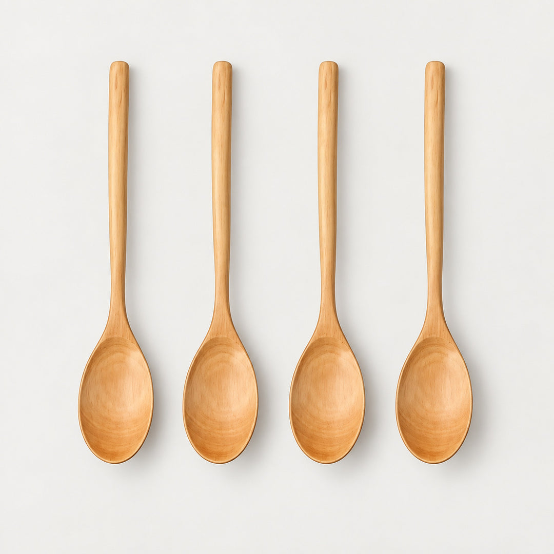 Four Camel wood spoons on a light warm-gray studio background.