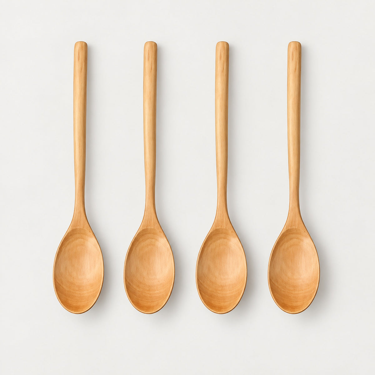 Four Camel wood spoons on a light warm-gray studio background.