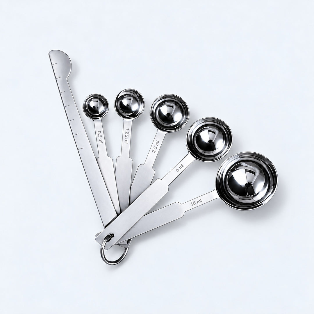Silver five-spoon set with flat leveler on a pale gray studio background.