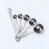 Silver five-spoon set with flat leveler on a pale gray studio background.
