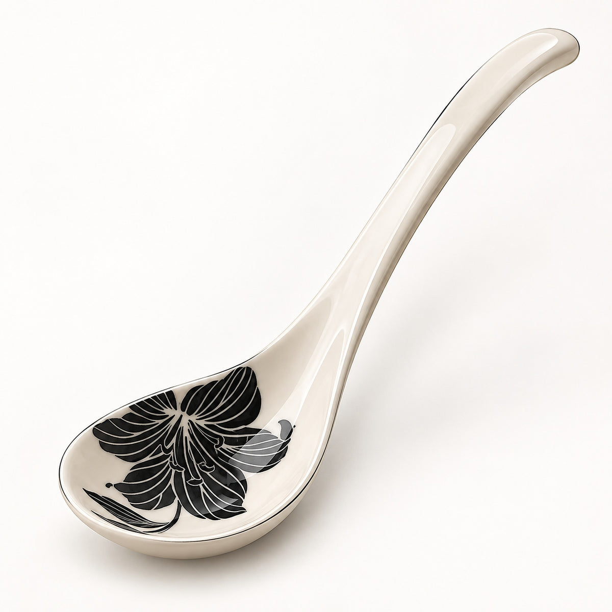 An off-white ceramic serving spoon featuring a black floral pattern on the bowl, set against a clean white background.