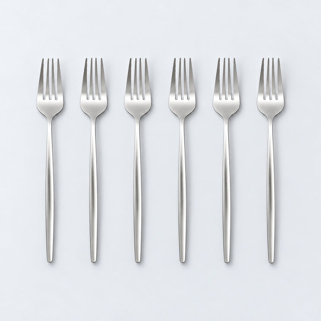Set of six silver dinner forks on a pale gray studio background.