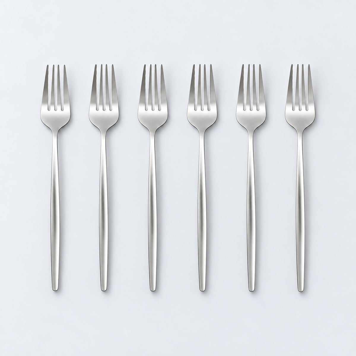 Set of six silver dinner forks on a pale gray studio background.