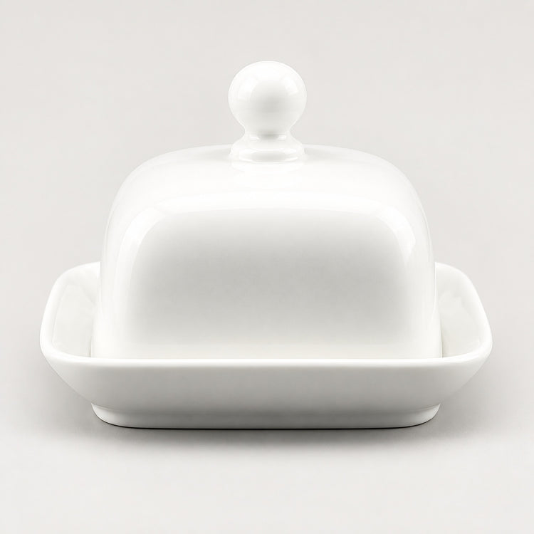 A white ceramic butter dish with a domed lid featuring a round knob and a shallow square base, photographed on a clean light gray background.
