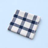 Single white with blue grid cotton towel, folded studio view.