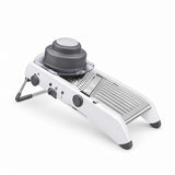 White adjustable mandoline with gray food holder on its steel deck.