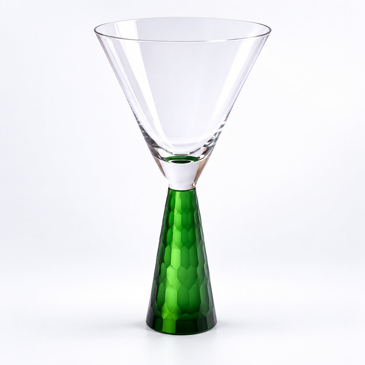 A clear glass martini-style glass with a faceted green stem, photographed on a clean white background.
