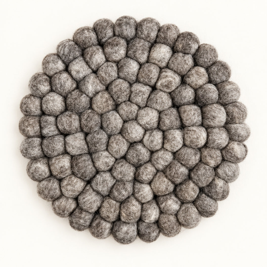 A round gray felt placemat made of textured, raised pom-pom balls, photographed from directly above on a clean white background.