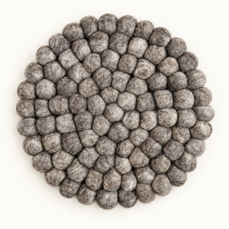 A round gray felt placemat made of textured, raised pom-pom balls, photographed from directly above on a clean white background.