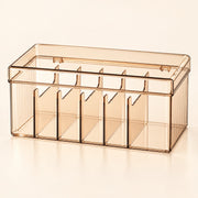 A translucent smoky amber plastic organizer box with multiple vertical compartments and a hinged lid, shown on a clean off-white background.